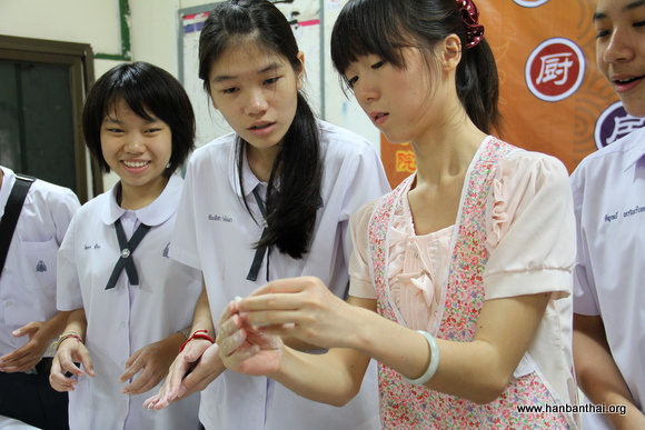 图片一：志愿者老师指导学生如何包饺子皮.JPG